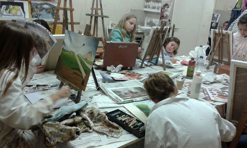 Alumnos en clase de pintura trabajando en sus cuadros